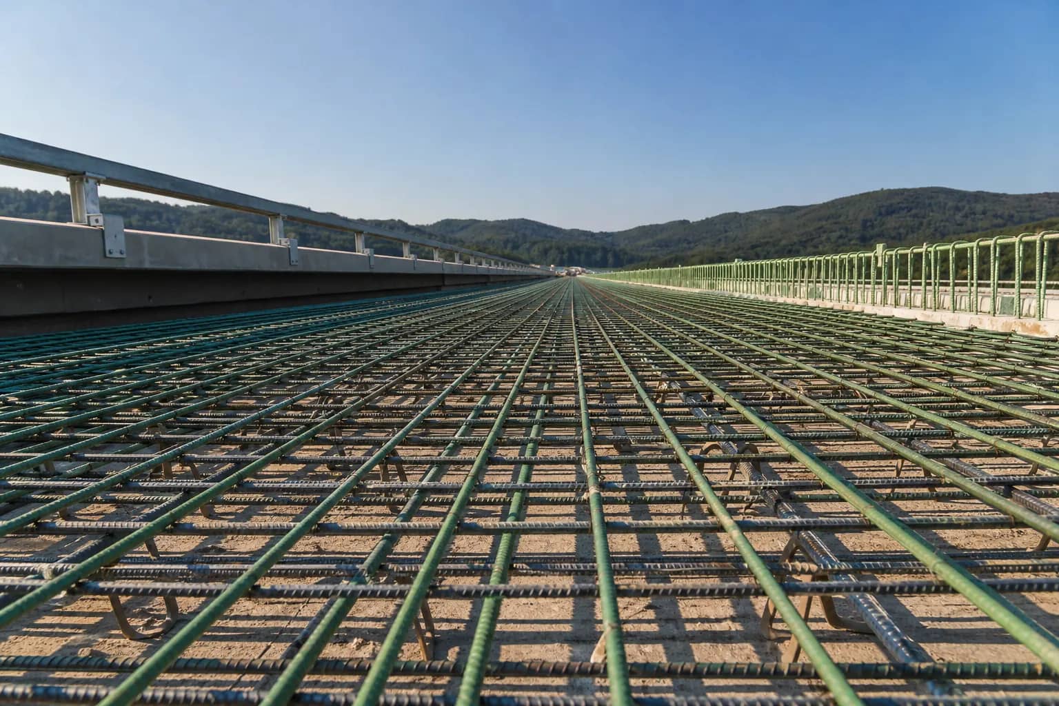 Epoxy-coated and bare reinforcing bars laid in a grid across a concrete bridge deck under construction