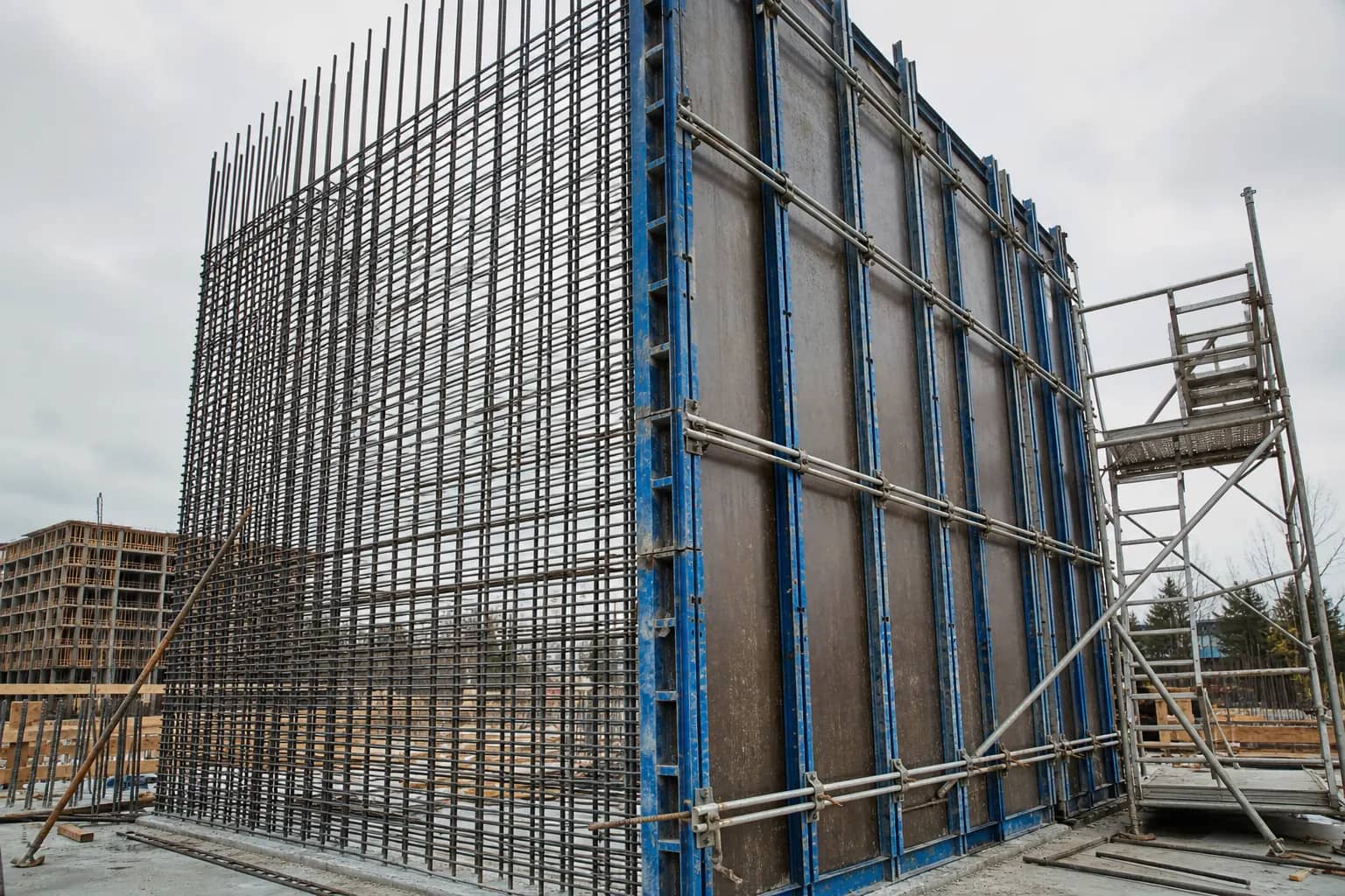Reinforced concrete shear wall under construction, with formwork panels on one face and the reinforcing curtain exposed on the other